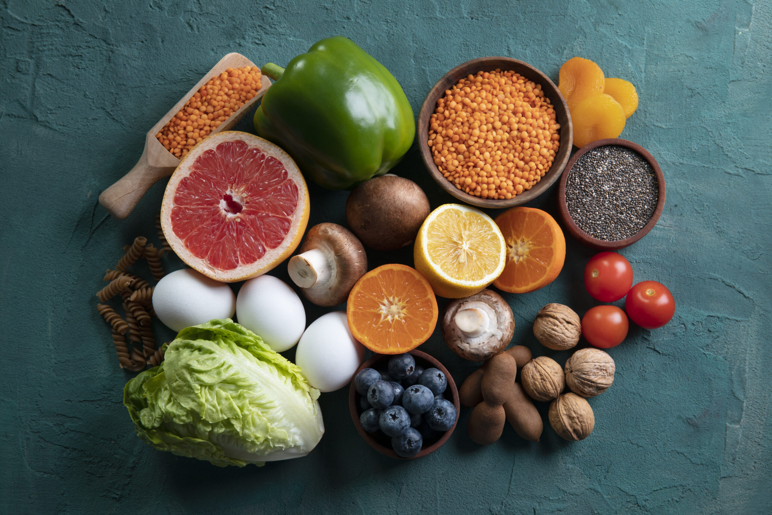 real-food-pyramid-arrangement Variety of whole foods including vegetables, eggs, nuts, pasta, lentils, dried fruit, and fresh fruit representing functional nutrition for optimal wellness
